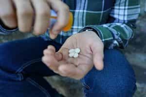 man pouring out too many antidepressants to feed his addiction