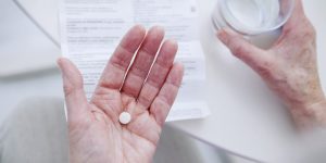 woman holding Zoloft pill in hand before taking it to treat depression