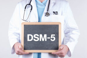 doctor holding chalkboard that says DSM-5, which is used when diagnosing substance use disorders